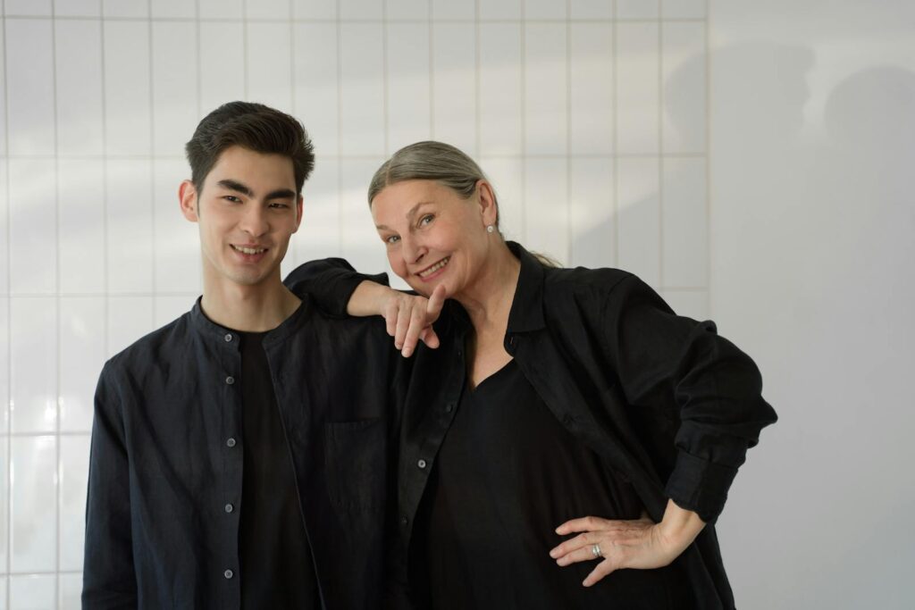 Smiling mother and son posing together indoors with a white background, reflecting warmth and togetherness.