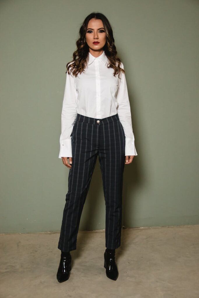 Confident young woman in a stylish striped pantsuit posing against a neutral background.