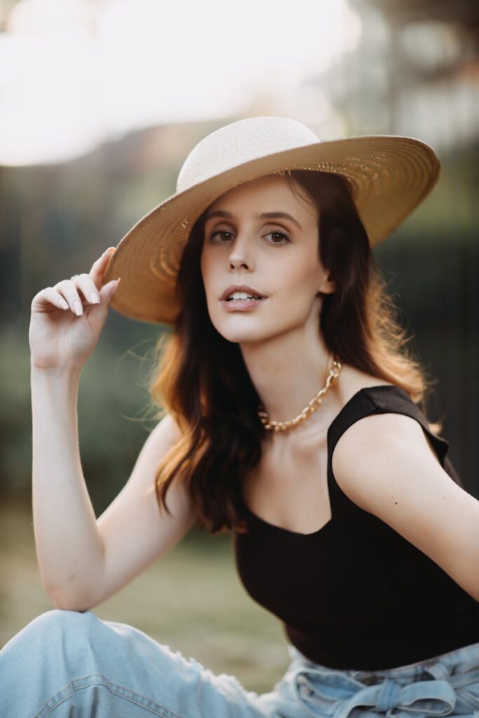 Stylish woman wearing a wide-brimmed hat and necklace outdoors, showcasing summer fashion.
