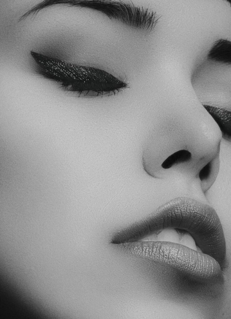Artistic black and white close-up portrait of a woman's face with glamorous makeup.