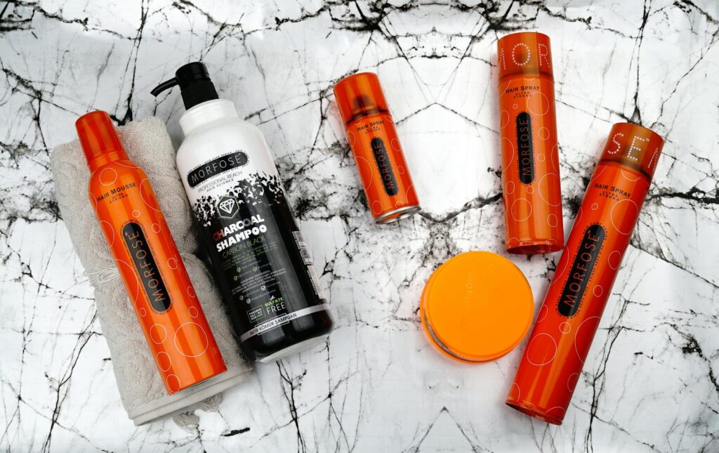 Flat lay of Morfose hair care products including mousse and charcoal shampoo on marble.