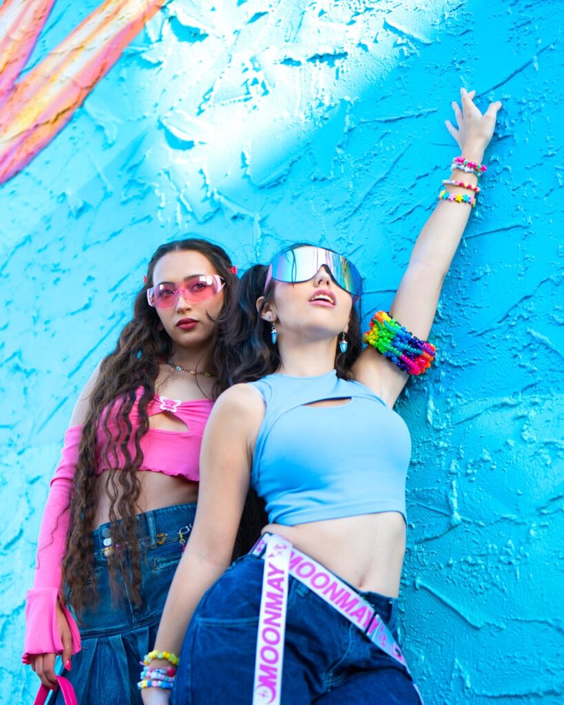 Stylish young women in colorful outfits posing against a blue wall.