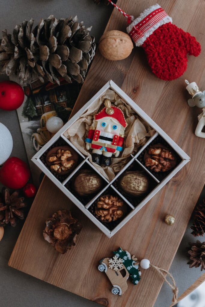 A top view of a Christmas-themed gift box with nuts and a decorative nutcracker.