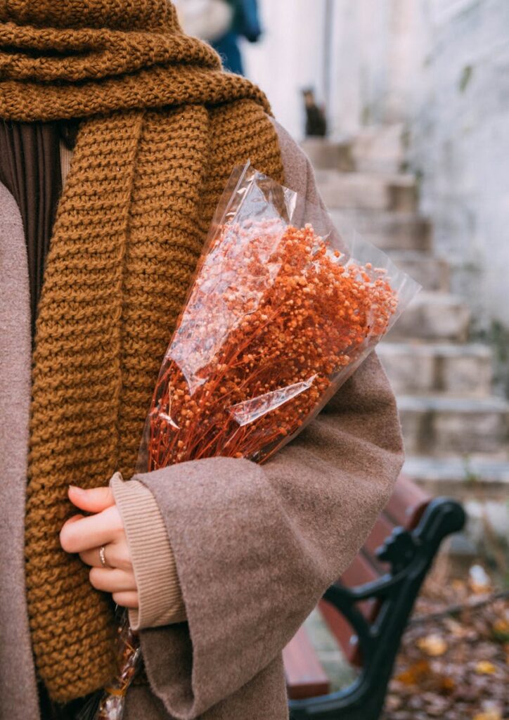 A woman in fall attire holding a dried flower bouquet on a street in İstanbul.