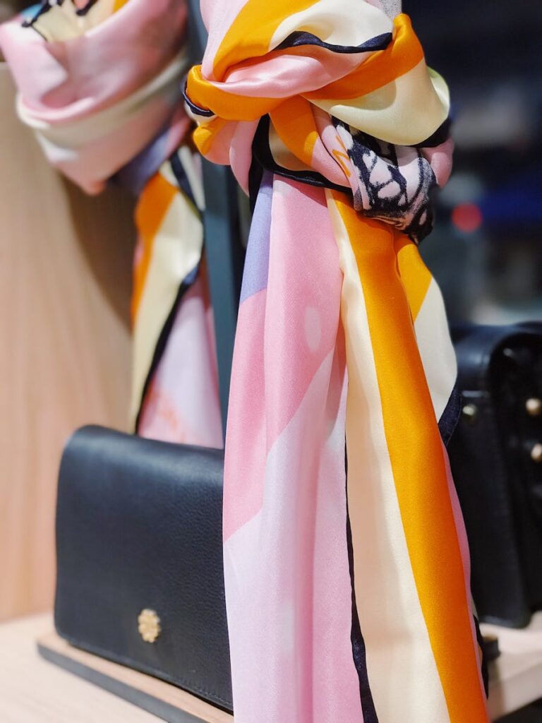 Close-up of a stylish silk scarf draped elegantly over a black designer handbag.