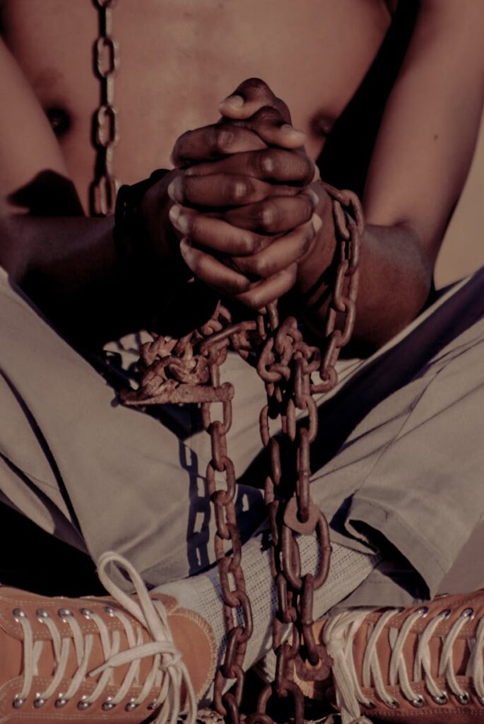 A powerful image capturing the essence of bondage and struggle through a chained man's posture.