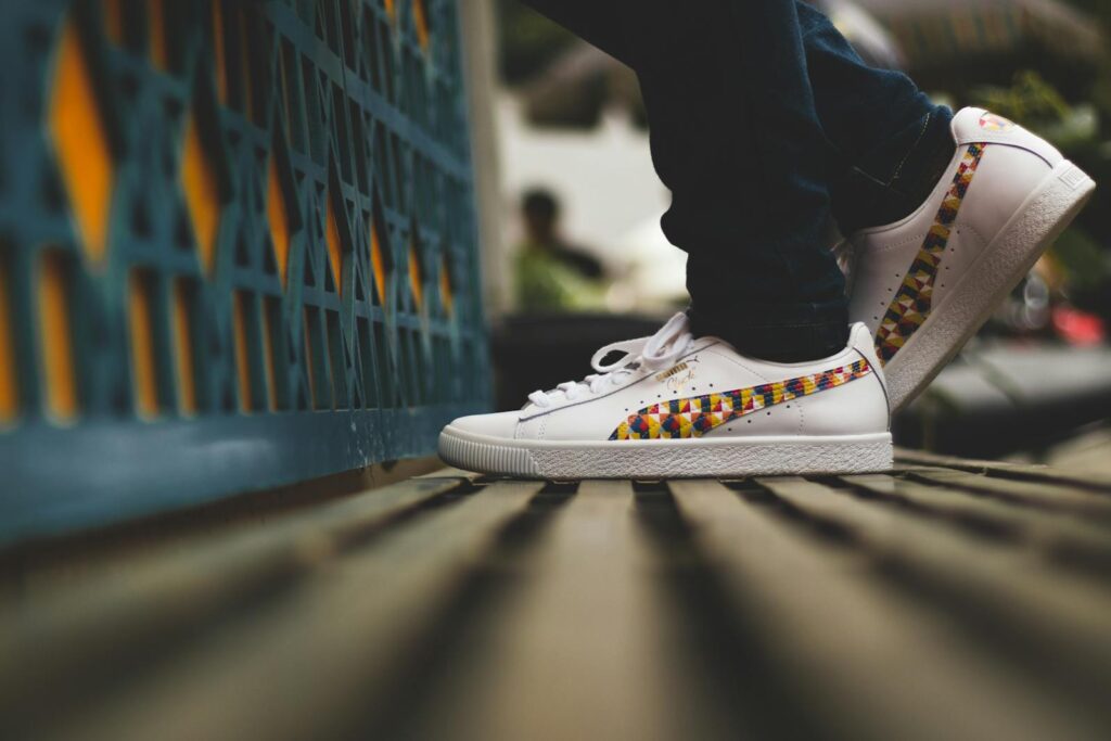 Close-up of stylish white sneakers with a colorful, geometric design, worn outdoors.