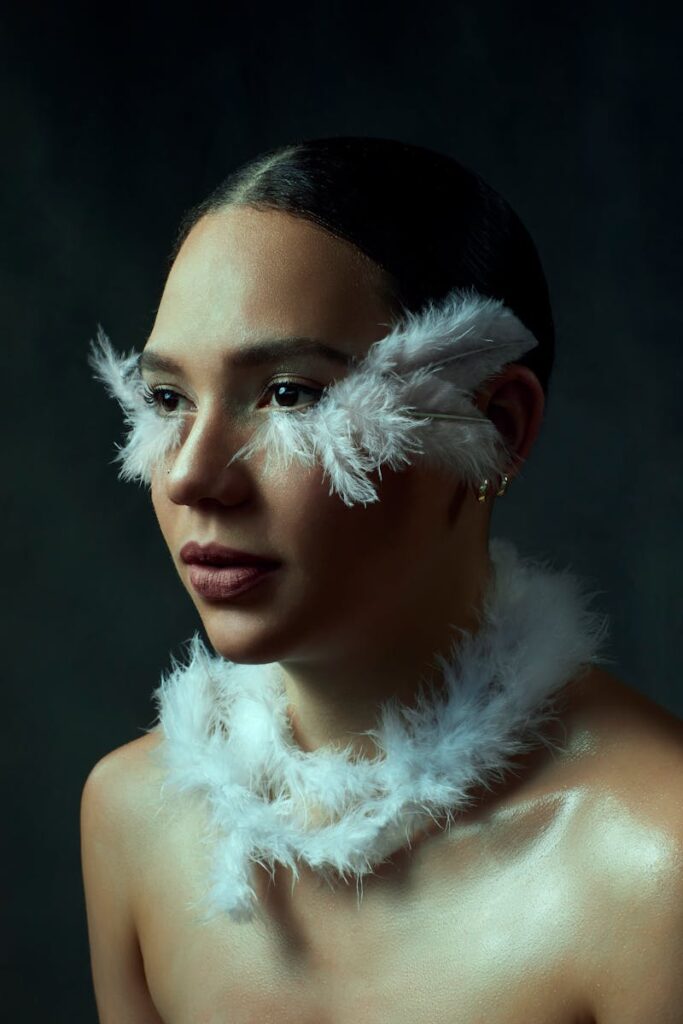 Elegant portrait of a woman with feather adornments against a dark background.
