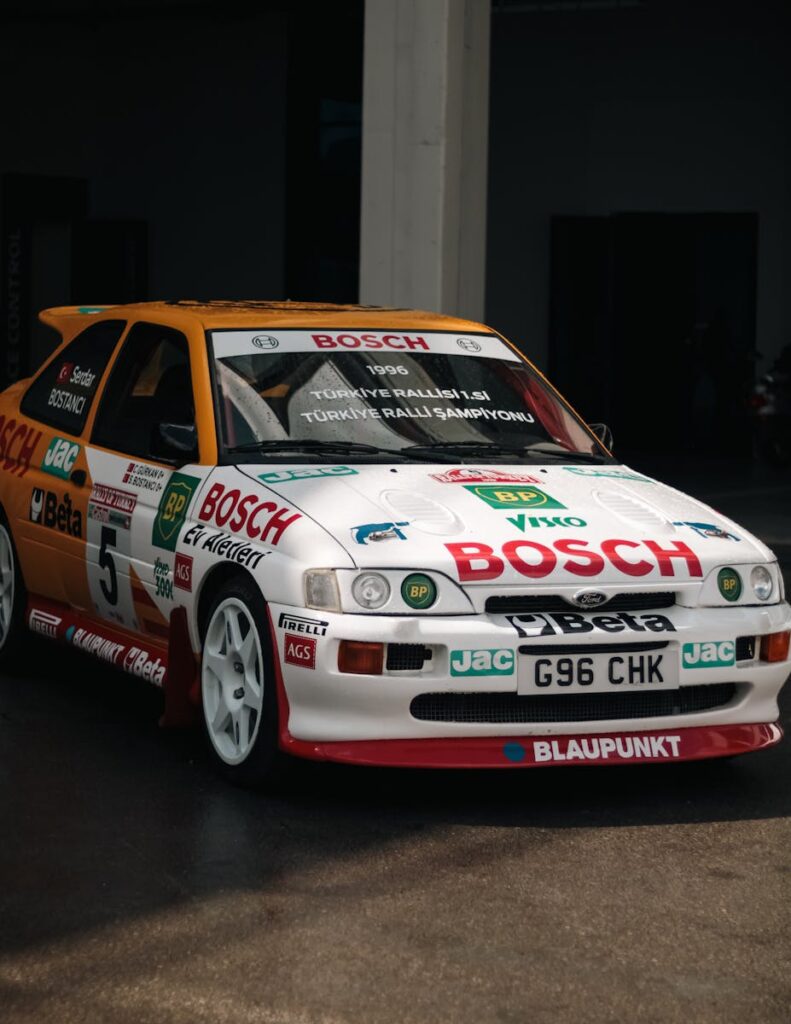 Classic rally car with sponsor logos, indoors. No people present, ideal for racing themes.
