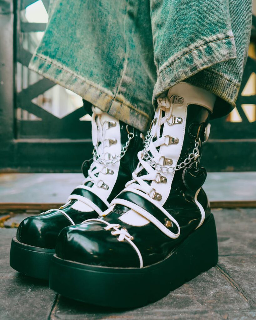 Trendy black platform boots with chains and denim jeans outdoors.