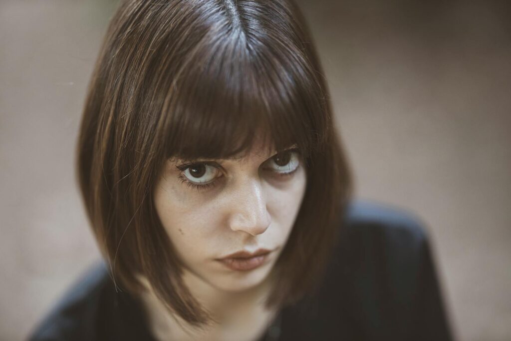 Close-up of a young woman with intense gaze and stylish bob haircut.