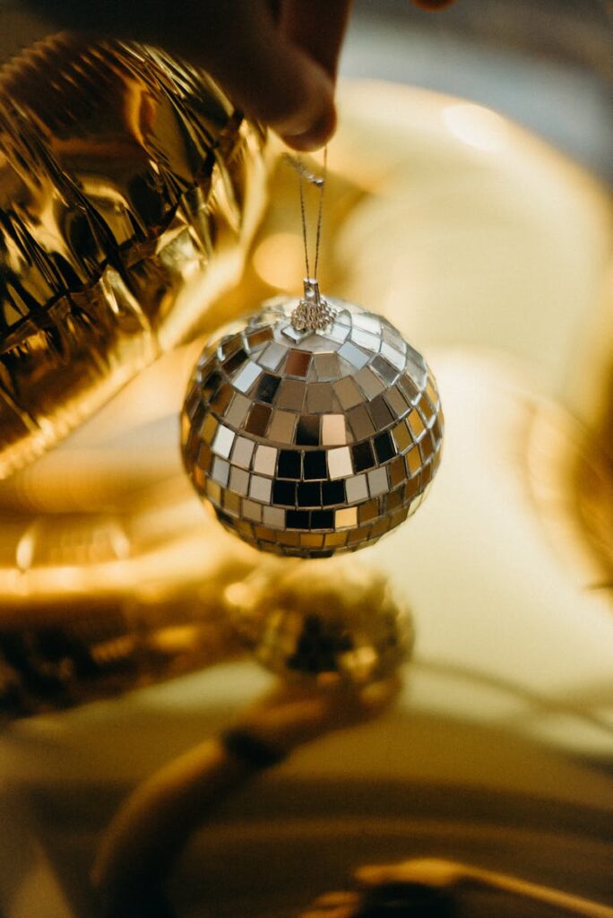 Shimmering disco ball held against a warm gold reflective background, creating a festive atmosphere.
