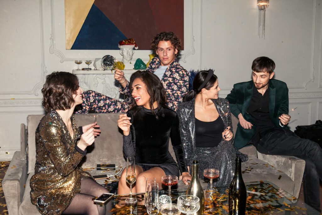 Group of adults in formal attire enjoying a lively party with drinks and laughter.