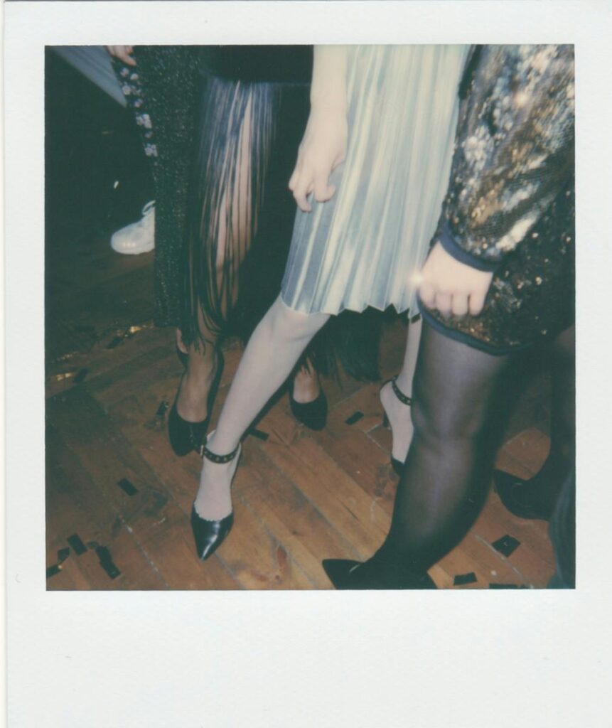 Stylish women in chic outfits and heels at a lively indoor party.