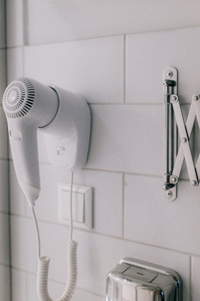 Clean white wall-mounted hair dryer in a contemporary bathroom setting.