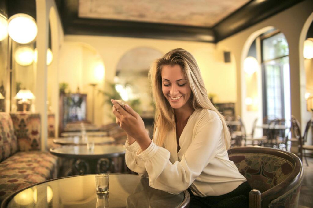 Cheerful woman enjoying her time with smartphone at a stylish indoor café.