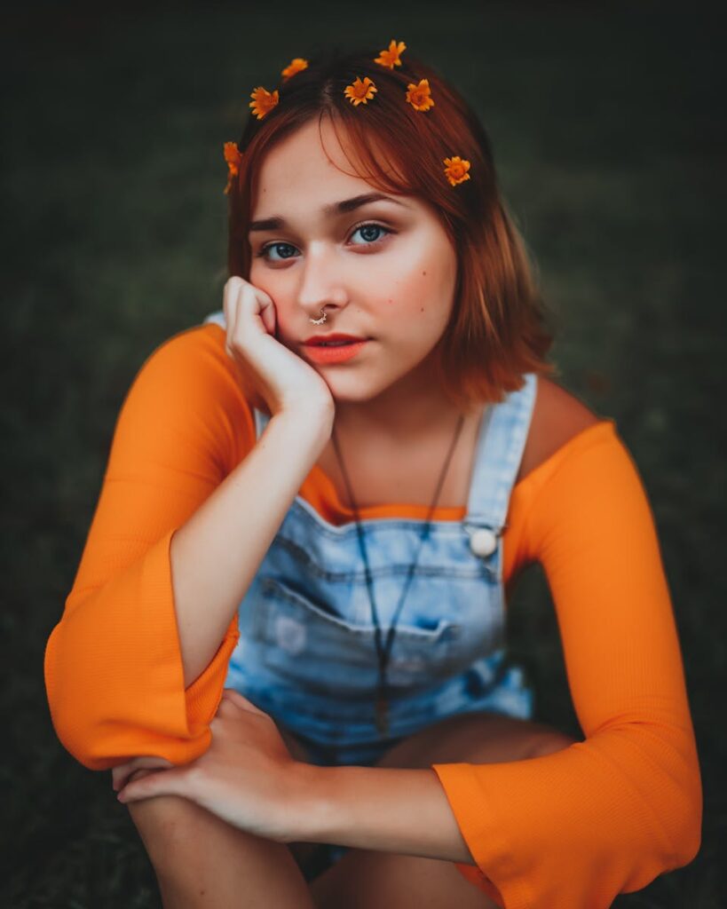 A young woman with floral hair accessories in a thoughtful pose outdoors.