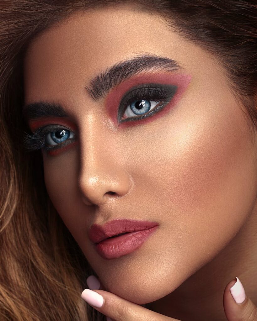 Close-up portrait of a woman with striking blue eyes and bold makeup.