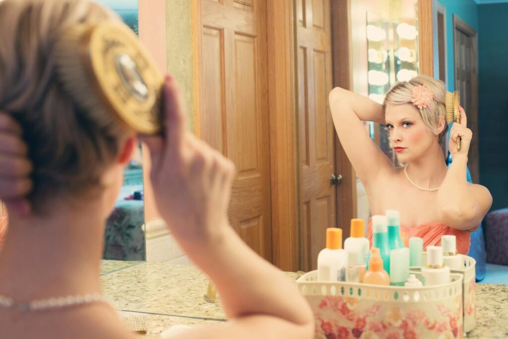 A woman elegantly brushing her hair in front of a mirror, capturing a vintage style.