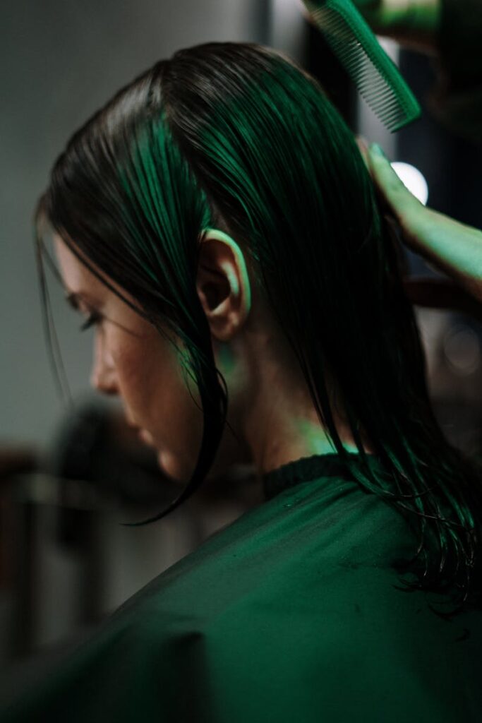 Side view of a woman getting a haircut with wet hair in a salon setting.
