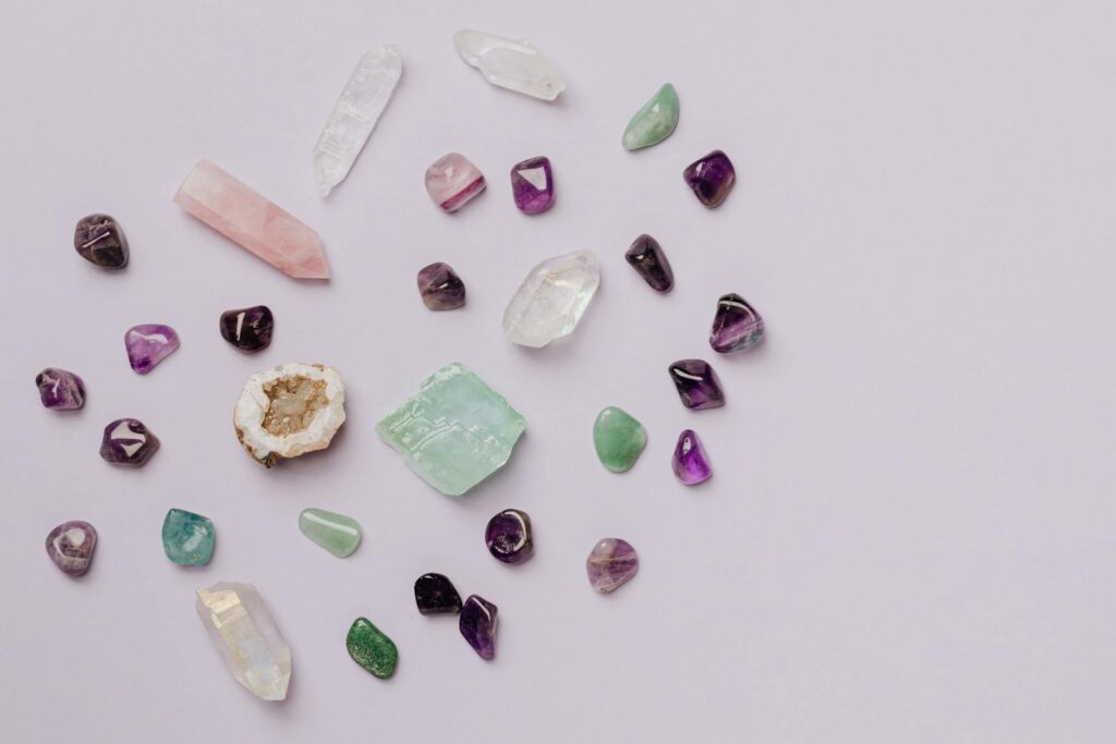 A collection of various crystals and gemstones arranged on a minimalist light surface.