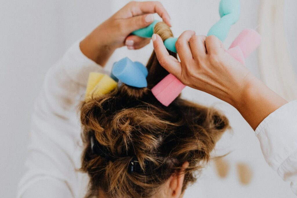 Woman styling hair with soft foam curlers in a close-up view.