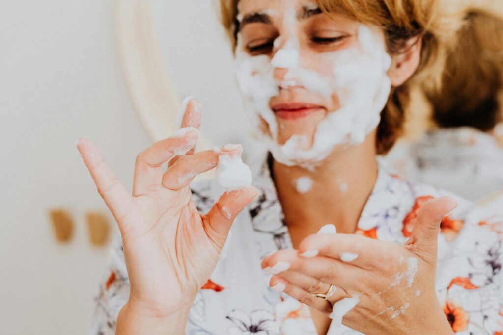 Woman having fun with a bubble face mask during her skincare routine, smiling and applying foam to her face.