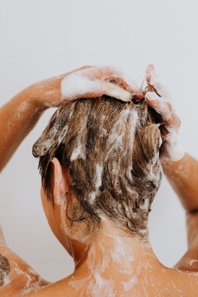 Close-up of a woman washing hair with foam shampoo, focused on hygiene and care.