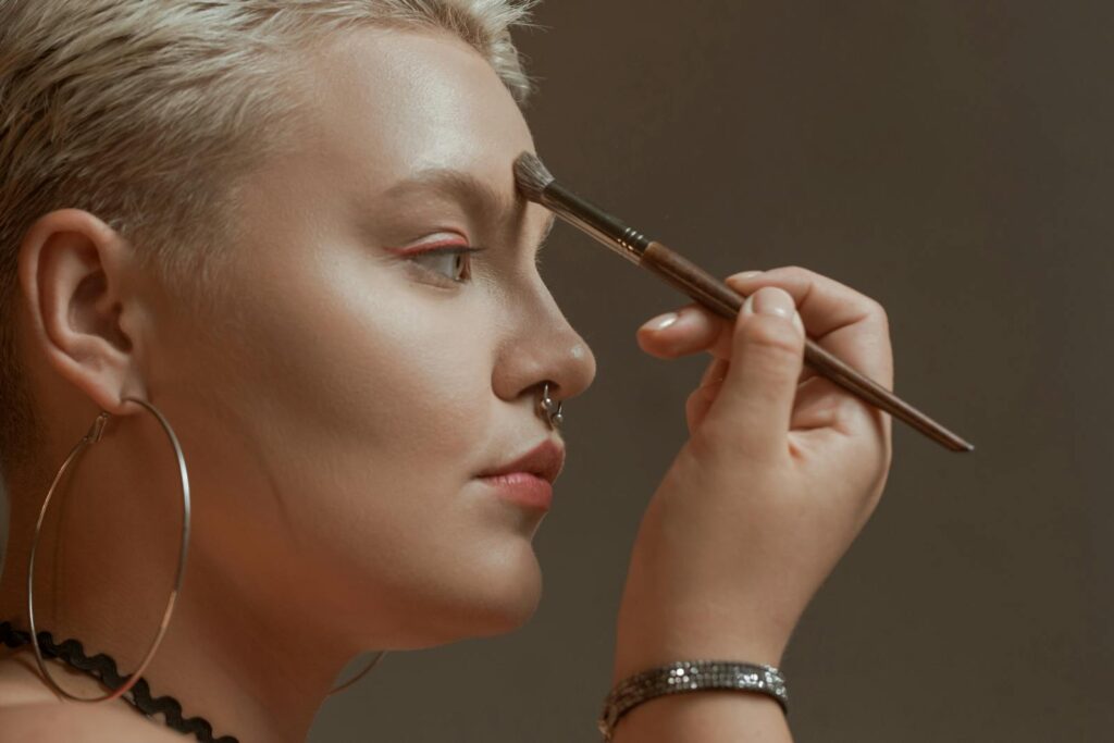 Close-up of a woman applying makeup with a brush, featuring jewelry and a stylish look.