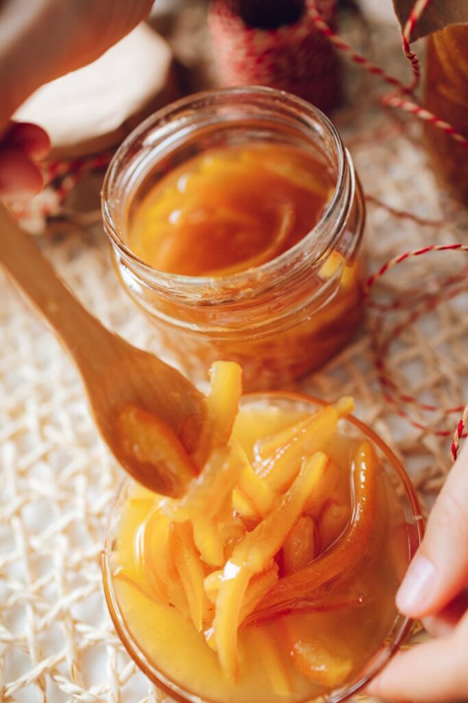 Delicious homemade orange jam in a jar with a wooden spoon for serving.