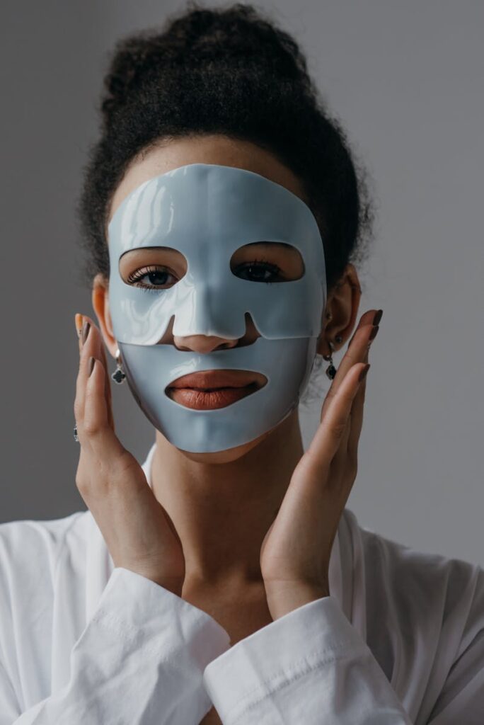 Close-up of a woman applying a facial mask as part of her skincare routine indoors.