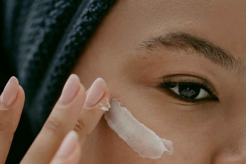 Extreme close-up of a woman applying cream to her cheek for healthy skin care.