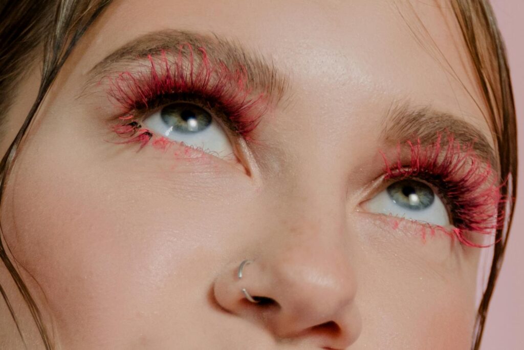 Close up image showcasing vibrant red eyelashes and trendy makeup on a woman.