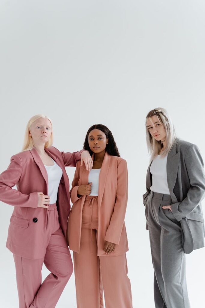 Three diverse women in elegant blazers posing confidently against a white backdrop.