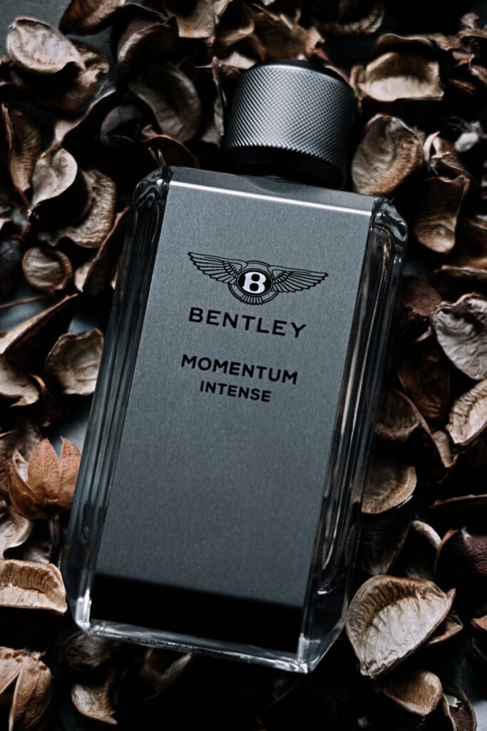 Luxurious Bentley Momentum Intense perfume bottle surrounded by dried petals, evoking elegance.