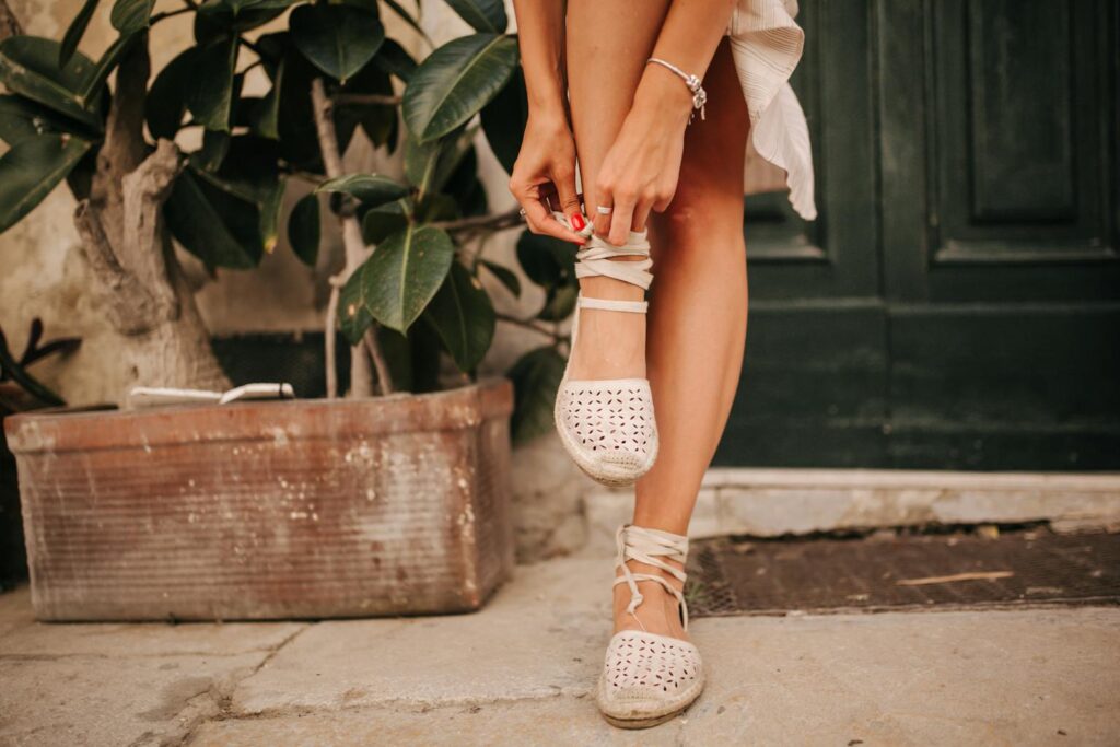 Close-up of a woman tying espadrille shoes on a warm day.