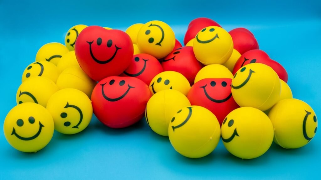 A collection of vibrant yellow and red smiley stress balls arranged on a blue surface.