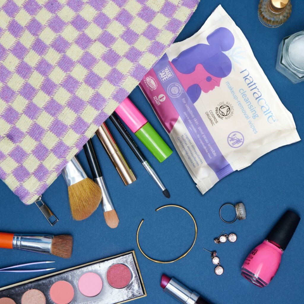 The contents of a makeup bag laid out on a blue surface