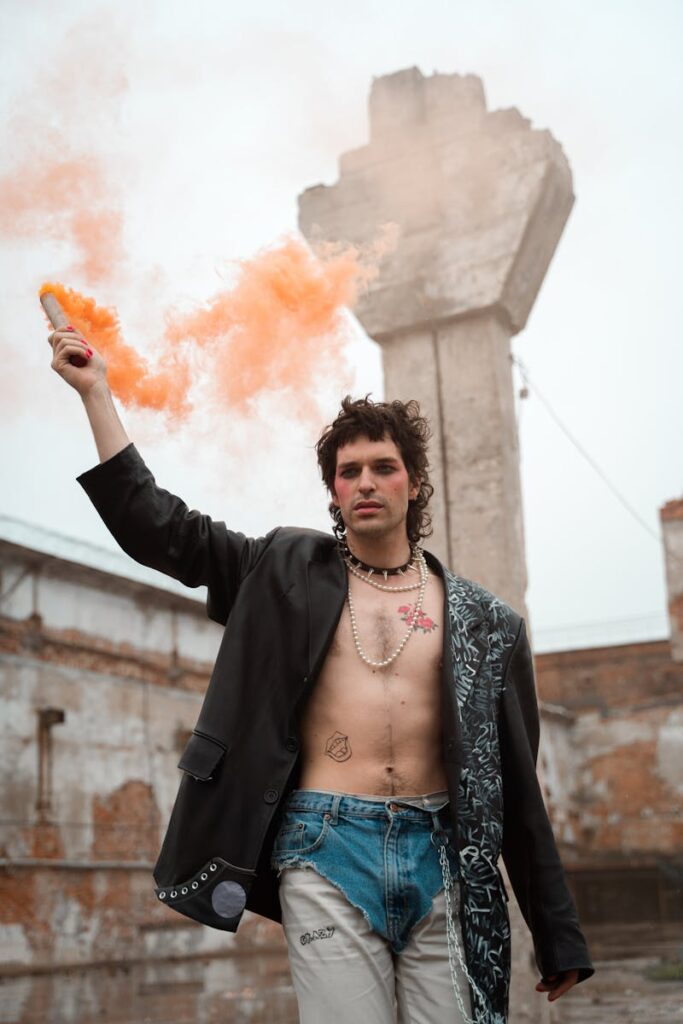 Model showcases punk fashion with smoke bomb outdoors against concrete backdrop.