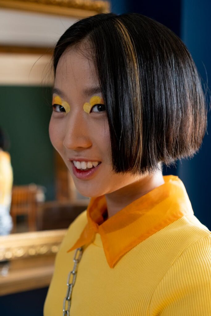 Colorful portrait of a young woman with artistic makeup and fashion indoors, showcasing style and creativity.