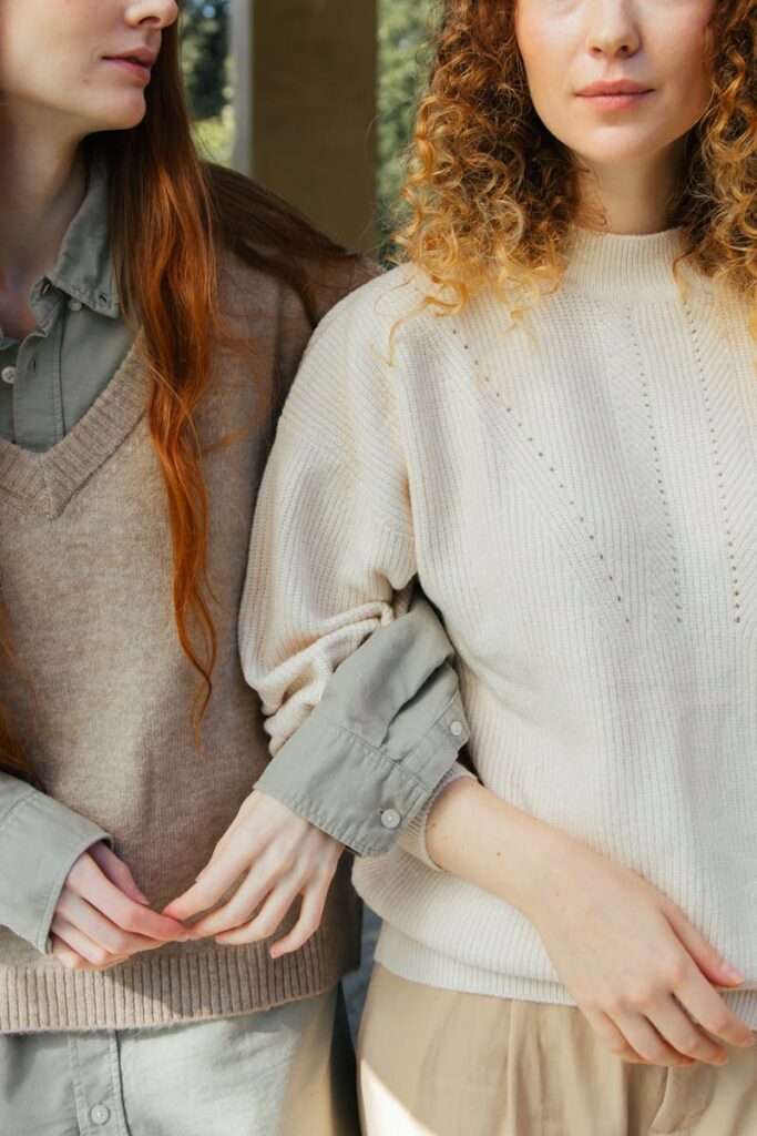 Close-up of two women standing arm in arm, showcasing knit fashion and friendship.