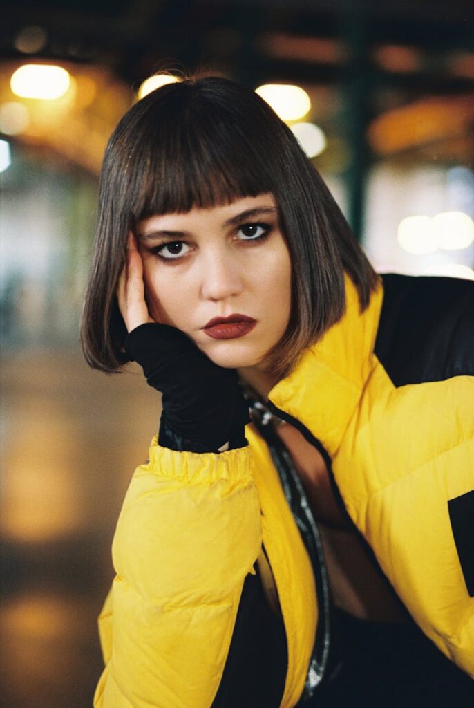 Portrait of a stylish woman wearing a yellow jacket indoors with a moody ambiance.