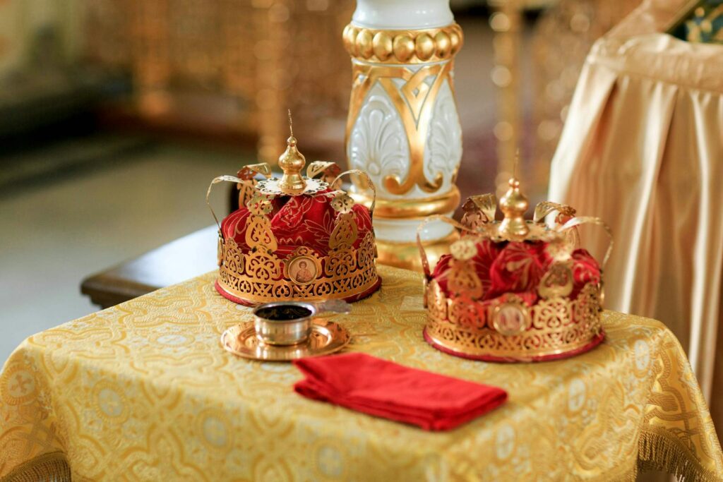 Golden crowns on a decorated table with ornate details, evoking royalty and ceremony.