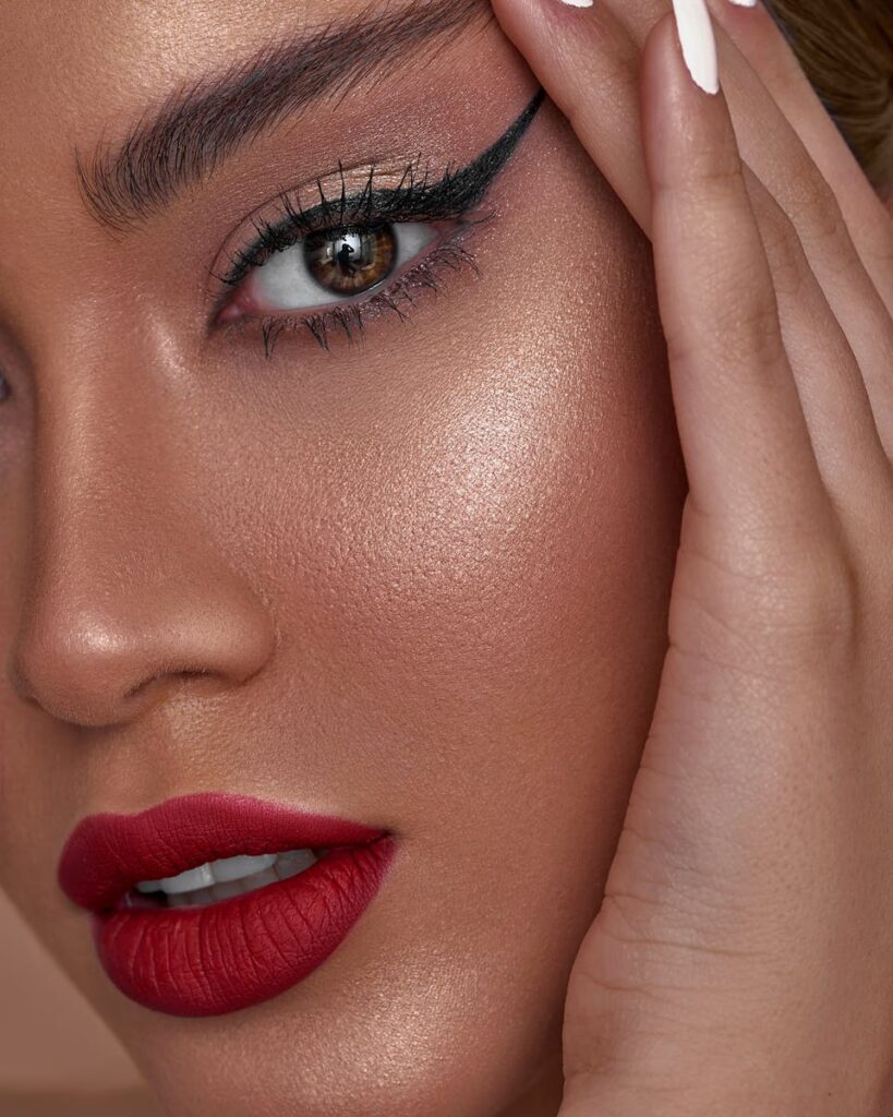 Vibrant close-up portrait featuring bold eye makeup and red lips, highlighting flawless skin.