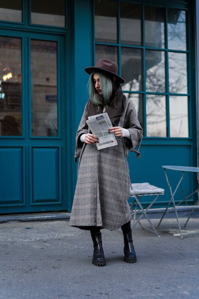 Fashionable woman with colored hair and fedora reads newspaper in Tehran. Urban street style.