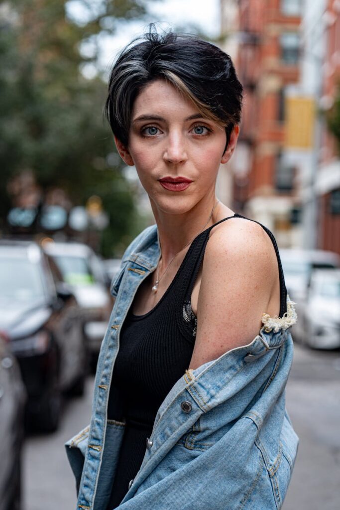 Fashionable woman posing in denim jacket on a vibrant New York street.