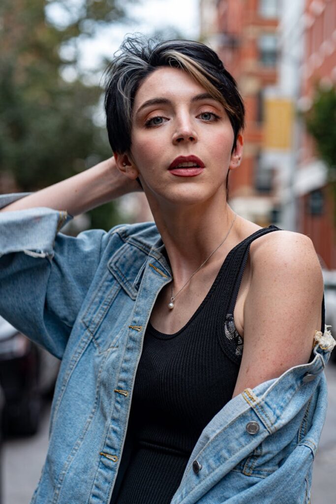 Fashionable model in a denim jacket poses in vibrant New York urban backdrop.