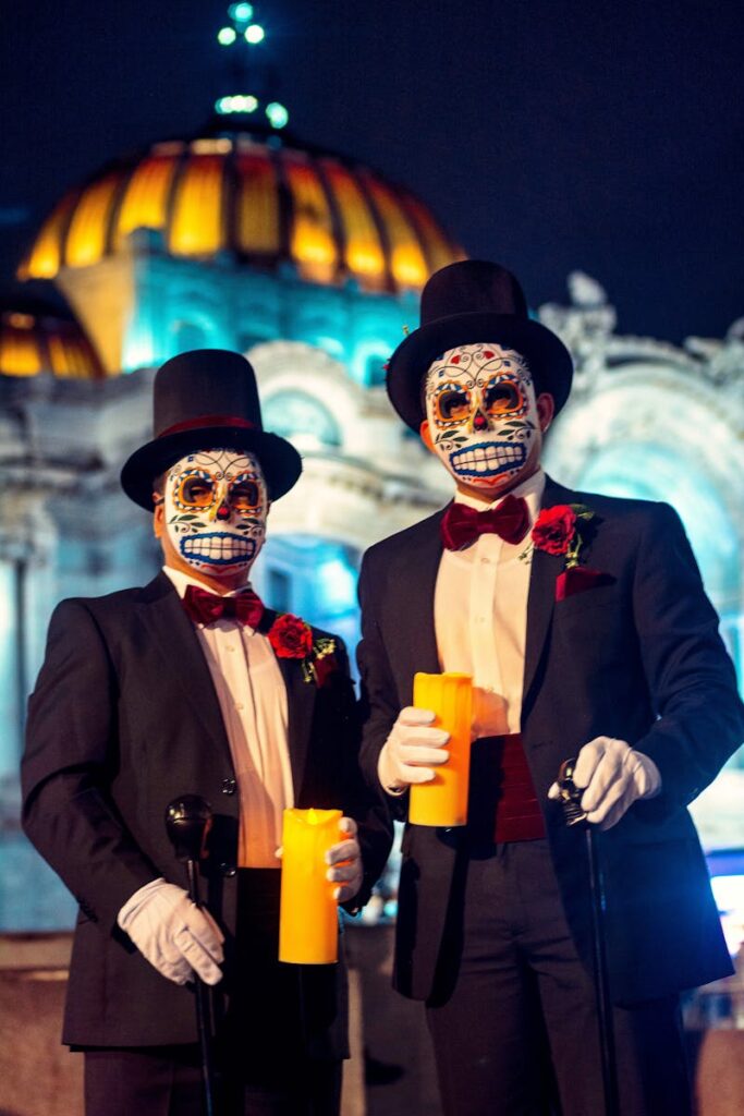 Men in Día de Muertos makeup holding candles by Palacio de Bellas Artes, Mexico City.