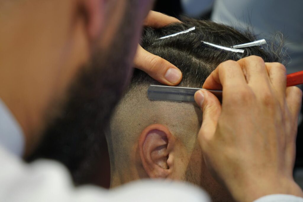 A barber uses a razor for precise grooming during a haircut in a modern barbershop.