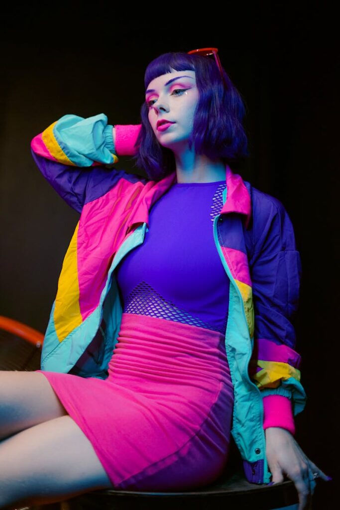 Stylish young woman in neon fashion posing with vibrant lighting in a studio.